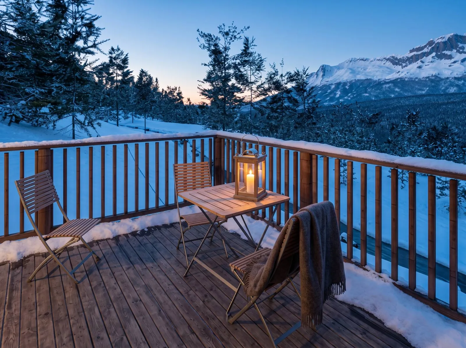 Deck with a small table, chairs and a lantern above a creek